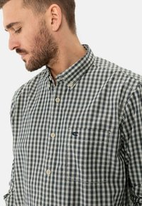 Kurzärmliges Hemd mit Knopfleiste im navy-weißen Karomuster, ausgestattet mit einer aufgesetzten Brusttasche und einem kleinen gestickten Logo auf der Brust.