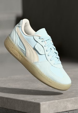 Baskets bleu clair avec un dessus texturé, des accents crème et une semelle en caoutchouc. Présente un design à lacets et des détails de marque sur le côté.
