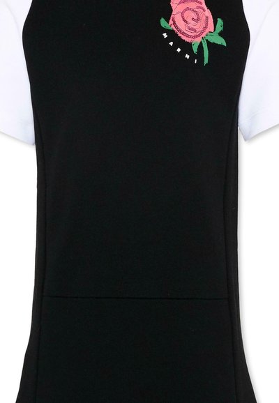 Robe noire sans manches portée sur un chemisier blanc à manches courtes avec une rose rose brodée et le logo "Marni" sur la partie supérieure de la poitrine.