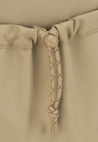 Tissu khaki avec une finition texturée, présentant un haut froncé avec un cordon de serrage beige réglable et une fermeture à bascule ronde.