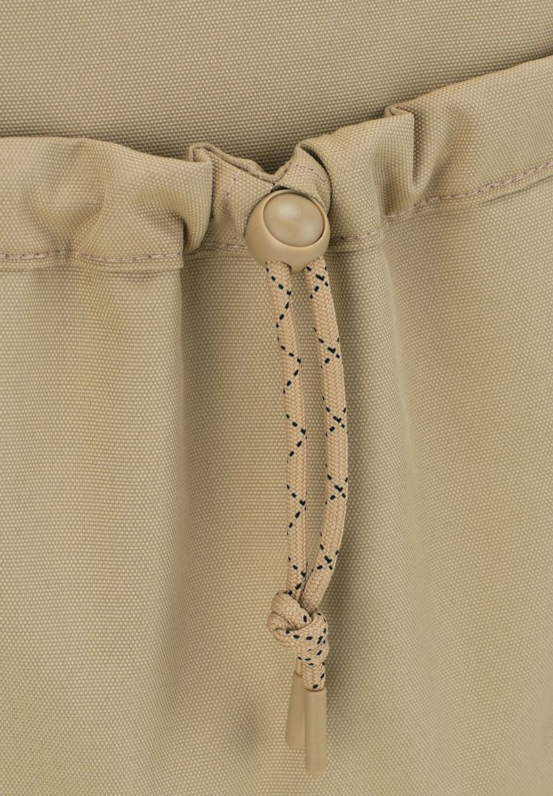 Tissu khaki avec une finition texturée, présentant un haut froncé avec un cordon de serrage beige réglable et une fermeture à bascule ronde.