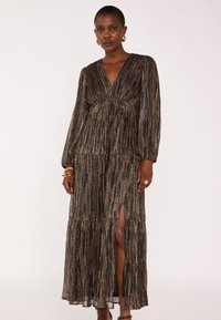 Robe maxi en tissu bronze foncé, dotée de plis verticaux, décolleté en V, manches longues et fente sur le côté. Agrémentée d'un design superposé.