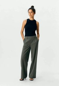Black sleeveless top paired with high-waisted, wide-leg olive green trousers. Smooth fabric, tailored design, and minimalist styling.