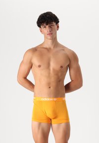 Narancssárga pamut boxer alsónadrág, fehér adidas logóval a deréknál, illeszkedő kialakítással és sima textúrával.