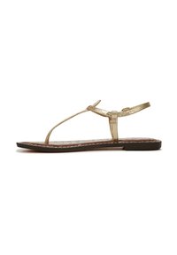 Sandalo piatto in metallo dorato con design a T-strap, dotato di una soletta marrone texture e una costruzione elegante e minimalista.