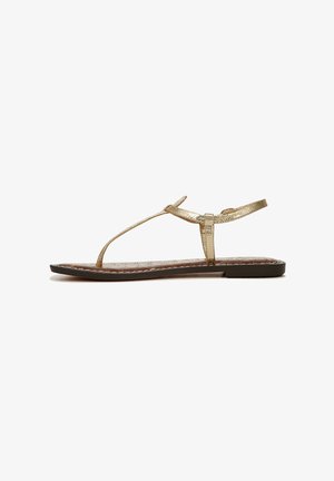 Sandalo piatto in metallo dorato con design a T-strap, dotato di una soletta marrone texture e una costruzione elegante e minimalista.