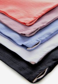 Stak af fem bomulds t-shirts i koral, lavendel, lyseblå, hvid og navy. Hver har en rund halsudskæring og synlige syningsdetaljer.