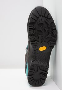 Black outsole with deep treads, featuring a Vibram logo and a yellow accent. Upper section has blue and gray highlights.