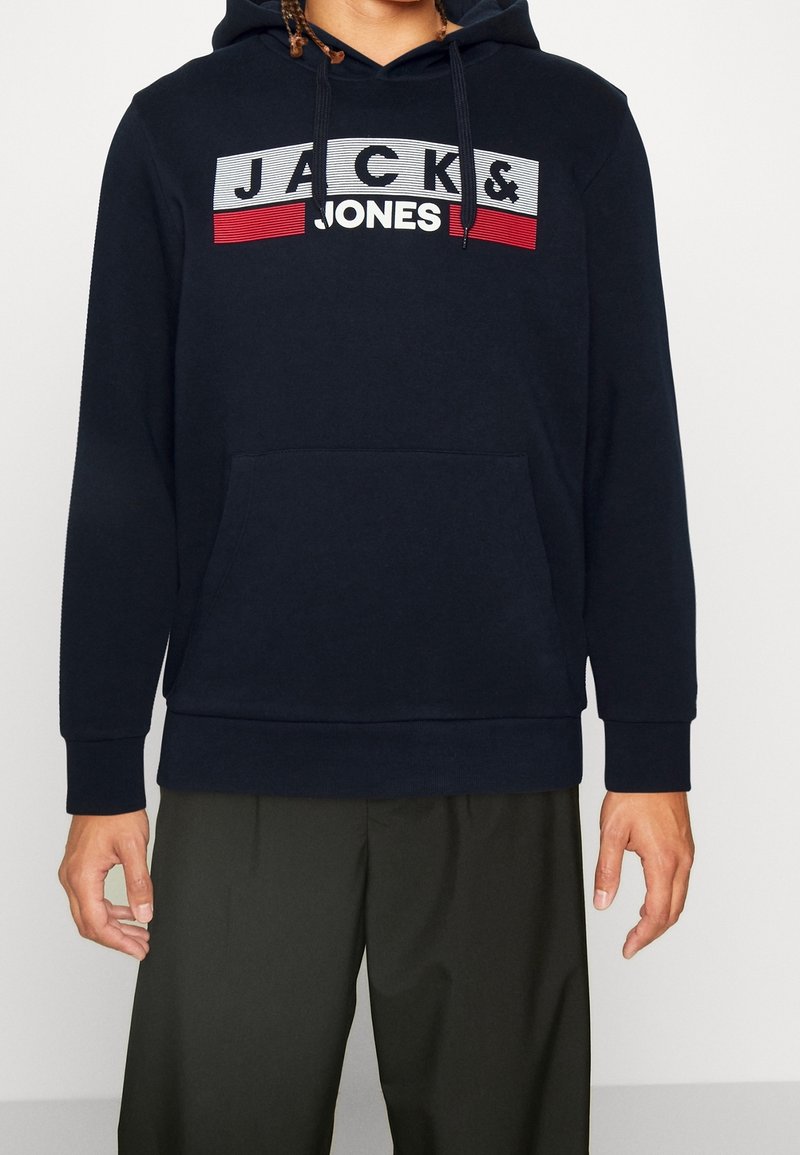 Felpa blu navy in misto cotone, con tasca a marsupio frontale e una grafica con logo "JACK & JONES" sul petto in rosso e bianco.