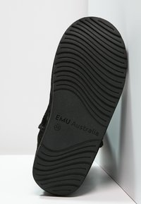 Calzature nere con suola in gomma testurizzata caratterizzata da motivi ondulati e con "EMU Australia" in rilievo. Il materiale superiore sembra morbido e peloso.