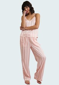 Conjunto de pijama de satén rosa con rayas verticales; incluye una blusa sin mangas y pantalones de corte suelto. Textura suave, diseño ligero.