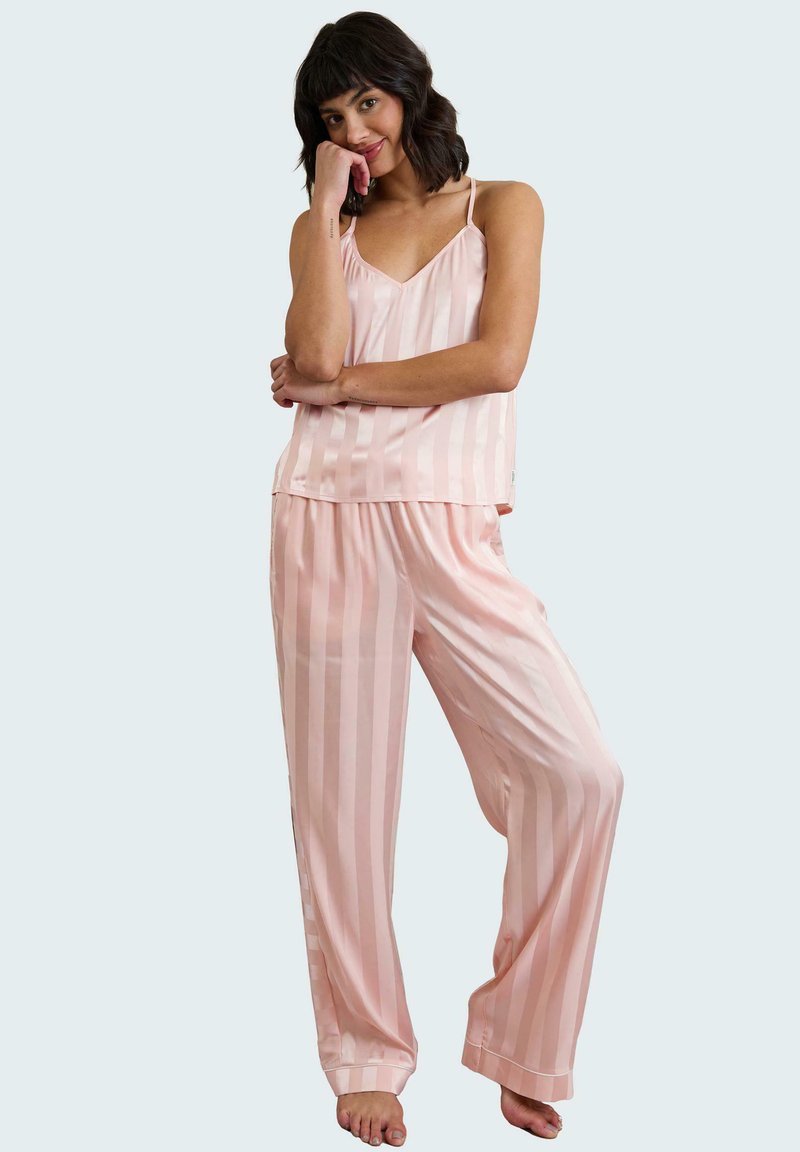 Conjunto de pijama de satén rosa con rayas verticales; incluye una blusa sin mangas y pantalones de corte suelto. Textura suave, diseño ligero.