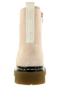 Botín de ante beige hasta el tobillo con suela gruesa marrón, medio suela cosido en negro, una lengüeta vertical blanca etiquetada "BULL BOXER" y cremallera lateral.