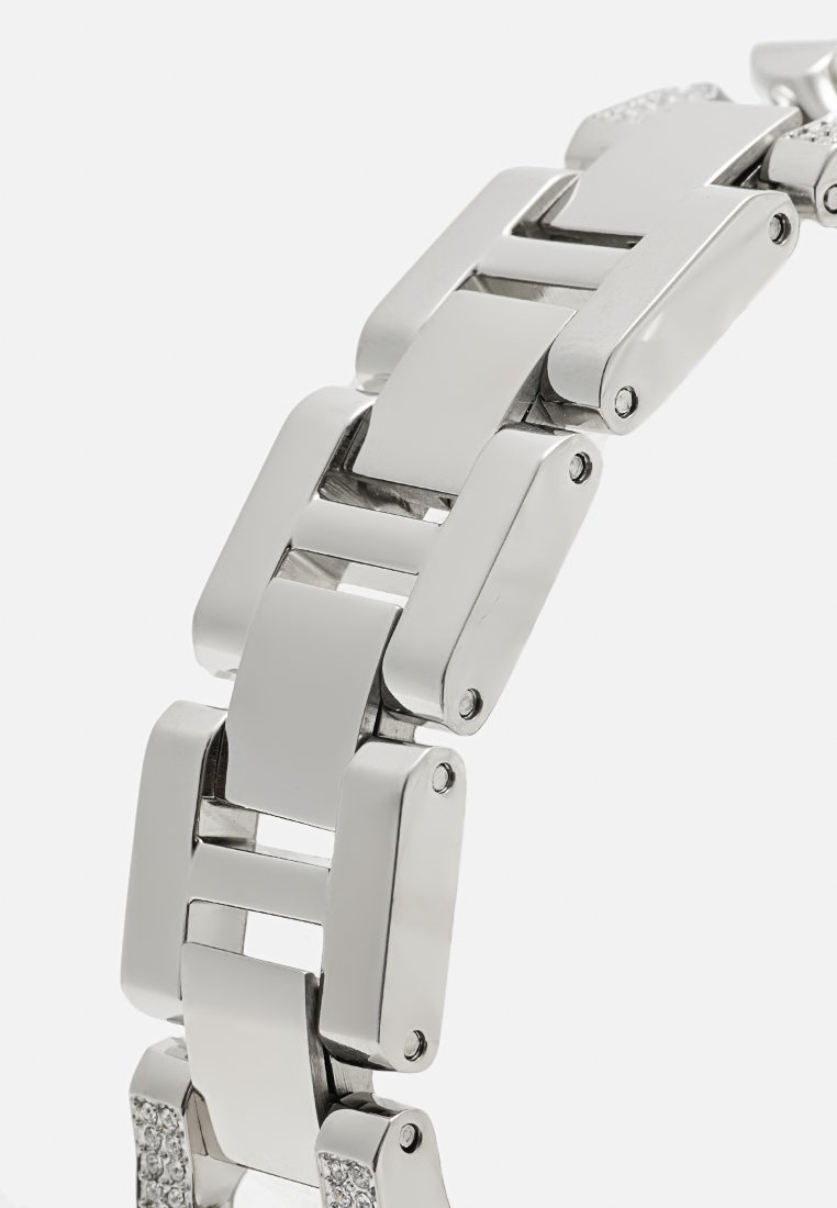 Glänzende Armbandglieder aus silbernem Metall, verbunden mit kleinen Schrauben, mit einem glatten, kantigen Design und einem Abschnitt mit eingearbeiteten klaren Steinen.