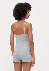Grå, ribbet tanktopp med tynne stropper, kombinert med matchende shorts. Stoffet er mykt med et teksturert mønster. Bakfra.