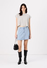 Világosszürke, rövidített felső, világoskék farmer miniszoknya, fekete hegyes orrú csizmák, fekete táska láncos pánttal. Egyszerű, letisztult design elemek.