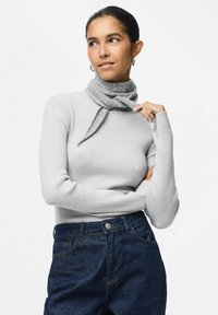 Grå, ribbet langærmet sweater parret med høj talje mørkeblå denim jeans. Et gråt strikket tørklæde er bundet om halsen.