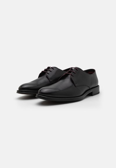 Schwarze Lederdressschuhe mit glatter Textur, runder Zehenpartie und zwei Ösen für Schnürsenkel. Schlanker Sohlenaufbau mit einem dezenten Absatz.