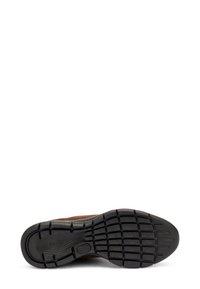 Zapato de ante marrón con una suela de goma negra texturizada que presenta un patrón de rejilla para mayor tracción. Sin herrajes ni acentos visibles.