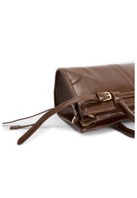 Brun læderhåndtaske med blød tekstur, udstyret med lynlås, aftagelig skulderrem og hardware i gull-tone.