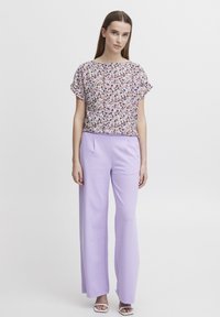 Paita bercorak bunga dengan lengan pendek, dipadukan dengan celana lavender bercorak lebar. Paita menampilkan warna-warna cerah; celana memiliki tekstur yang halus.