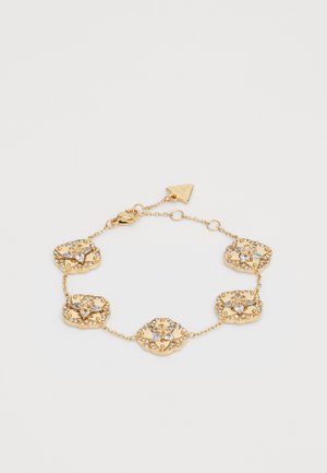 Bracelet en or avec des maillons ornés en forme de fleur, agrémentés de cristaux transparents, reliés par des segments de chaîne. Comprend un fermoir sécurisé et une étiquette avec le logo.