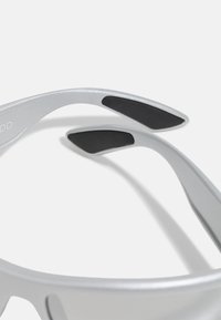 Silver sunglasses with lightweight frames, featuring black rubber accents on the inner side of the temple and a sleek, modern design.