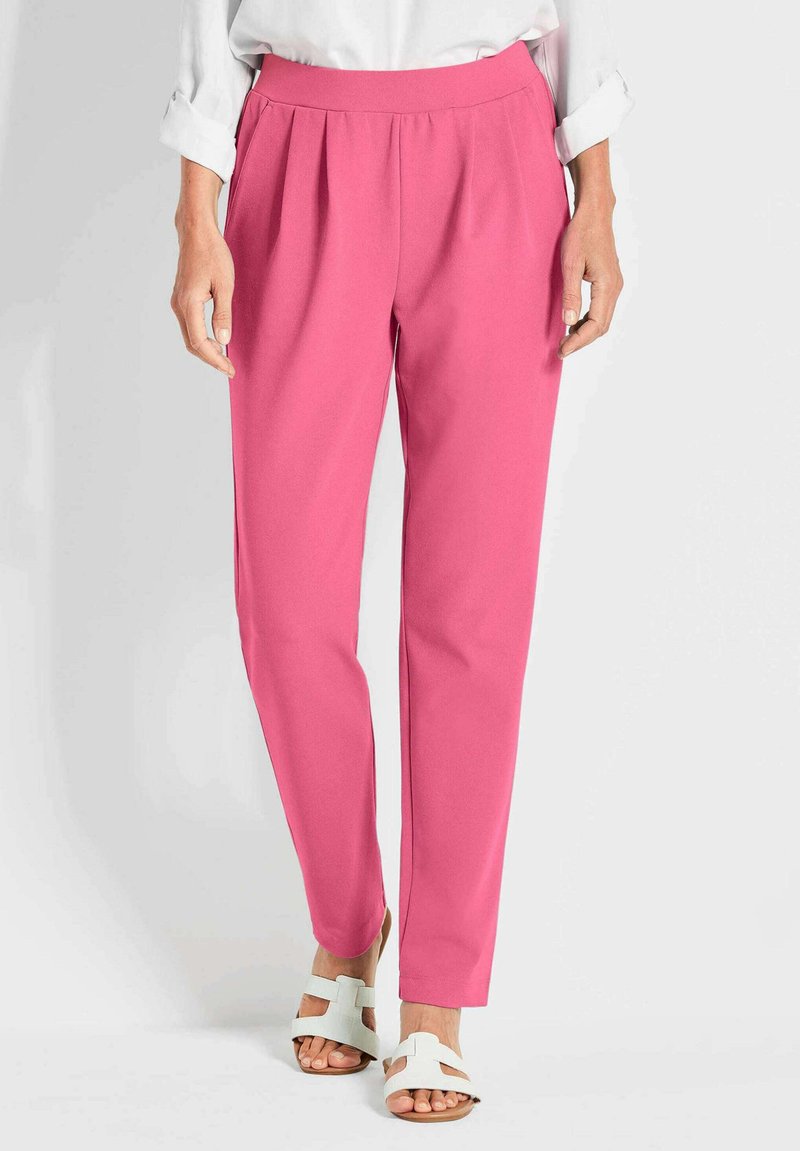 Roze op maat gemaakte broeken met plooien, gemaakt van lichte stof. Gecombineerd met witte sandaaltjes met bandjes. Eenvoudig ontwerp, recht model.