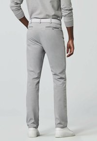 Light gray chinos with a slim fit, featuring back pockets, a textured white belt, and white sneakers. Smooth fabric with minimal detailing.
