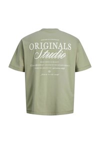 Camiseta de manga corta de color verde oliva claro con texto blanco en la parte trasera que dice "Originals Studio" y detalles de diseño más pequeños en varias tipografías.