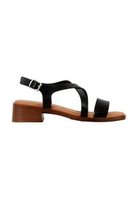 Sandalo in pelle nera con strap incrociati, fibbia regolabile alla caviglia e tacco medio impilato marrone. Texture liscia e design minimalista.