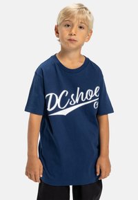 Námorně modré bavlněné tričko s bílým logem "DC Shoes" na hrudi, s krátkým rukávem a volným střihem.