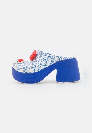 Weißer Clog mit blauem Hello-Kitty-Muster, roter Schleifenverzierung oben und klobigem blauem Plateauabsatz.