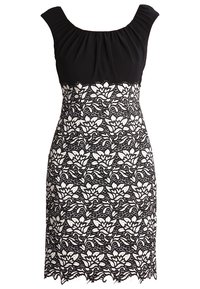 Robe noire avec un corsage texturé orné de détails froncés et une jupe en dentelle florale blanche, terminée par un ourlet festonné.