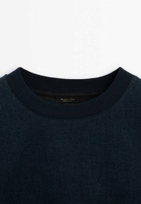 Laivastonsininen collegepaita, jossa on resorinen pyöreä pääntie. Kangas on pehmeää ja siinä on hienovarainen sävyeroilla muodostuva kuvio. Sisäetiketissä lukee "Made in Turkey".