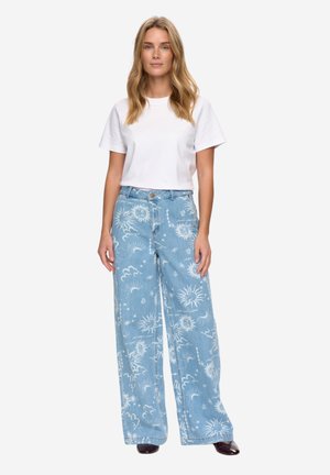 Svetlomodré džínsy s širokými nohavicami s bielym vzorom slnka a oblakov, doplnené o obyčajné biele tričko. Hladká textúra denimu, zapínanie vpredu na gombíky.