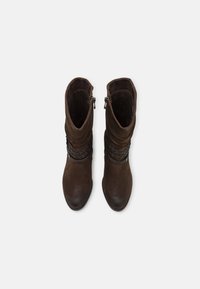 Braune Wildleder-Stiefeletten mit geflochtenem Detail und seitlichem Reißverschluss; glatte Textur und runde Zehenform.