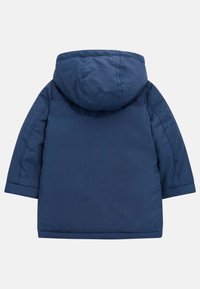 Tamsiai mėlynas gobtuvų švarkas su lygiu paviršiumi, paminkštinta konstrukcija ir ilgomis rankovėmis. Yra tiesus apdailos kraštas ir nematomas aparatūros vietas.