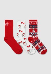 Tre calze a tema natalizio: una rossa uniforme, una bianca con faccine di Babbo Natale e fiocchi rossi, e una rossa con pupazzi di neve, bastoncini di zucchero e il testo "XMAS MERRY".