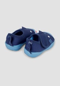 Chaussures pour enfants bleu marine avec un design de requin, dotées d'une sangle en Velcro, d'un dessus en tissu et d'une semelle en caoutchouc bleu clair. Détails remarquables en forme de nageoire de requin.