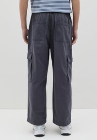 Pantaloni cargo grigi con una vestibilità ampia, dotati di due grandi tasche posteriori e tasche laterali cargo, realizzati in un tessuto dal tocco liscio.