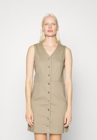 Vestido caqui sem mangas com decote em V, fecho frontal por botões, cintura ajustada e saia reta. Feito de um tecido suave com textura mínima.