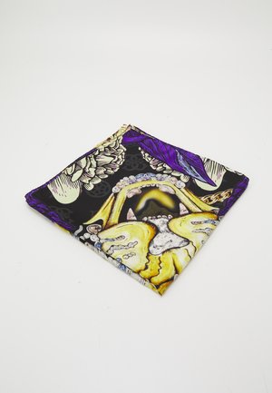 Pañuelo de seda doblado con diseño floral y de joyas en amarillo y púrpura sobre un fondo negro, sobre una superficie blanca.