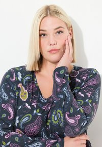 Långärmad topp i mörkgrått tyg med ett paisley- och blommönster i rosa, grönt och blått. V-ringning och figursydda ärmar.