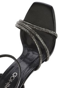 Black square-toed sandal featuring three metallic, beaded straps across the upper. Smooth texture with a shiny finish. Primark branding visible.