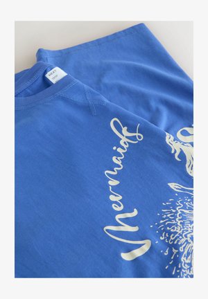 Blue sweatshirt folded with white cursive text reading "Mermaids" and partial sea-themed illustration on front.