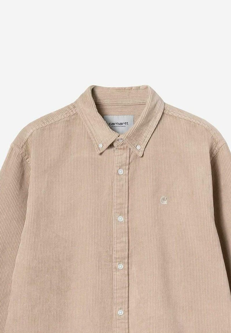 Beige kordfløjs skjorte med knapper og krave, hvide knapper og et lille broderet logo på brystet under kraven.