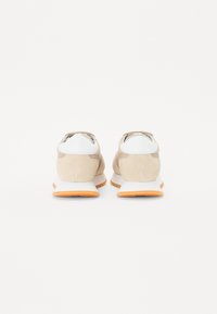 Baskets avec une tige en daim et mesh beige, accents blancs et semelle en caoutchouc orange. Talon rond avec un design subtil et fermeture à lacets.