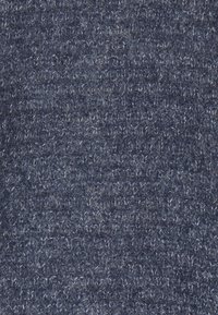 Tessuto lavorato a maglia navy con una superficie testurizzata e a loop. Le fibre appaiono morbide e leggermente lucide, creando una ricca profondità di colore.