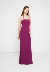 Axelbandslös, golvlång klänning i livfullt lila tyg. Figurnära silhuett med slät textur, utrustad med en sidodel för extra detalj.